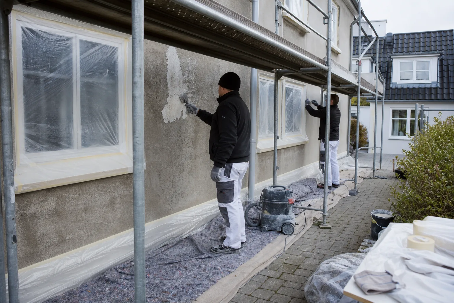 Afdækkede vinduer og stillads ved facademaling